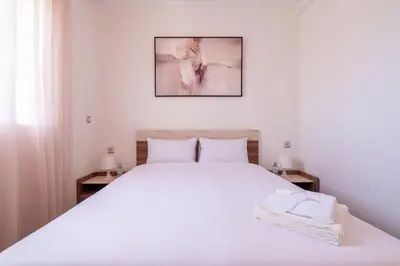 a bedroom with a large white bed with two tables at Appartement Premium avec Piscine in Mohammedia