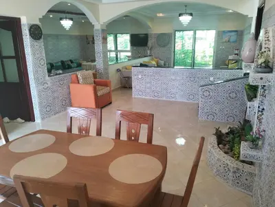 a dining room and kitchen with a table and chairs at RiadNA in Bouznika