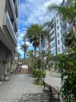 a bench in a courtyard with palm trees and buildings at le joyau de Parc Group A imm B in Mohammedia