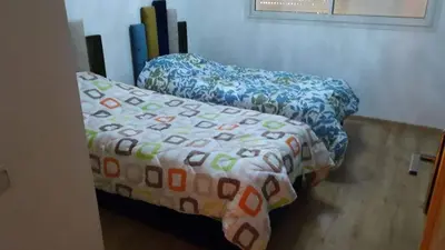 a bed with a comforter on it in a room at Appartement de luxe à 3 min de l aéroport in Nouaseur