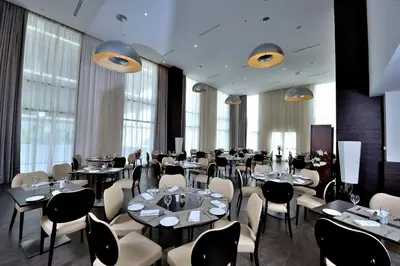 a dining room with tables and chairs and windows at Kenzi Sidi Maarouf in Casablanca