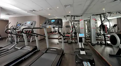 a gym with treadmills and machines in a room at Kenzi Sidi Maarouf in Casablanca