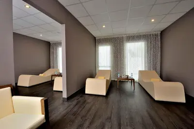 a waiting room with white chairs and tables and windows at Kenzi Sidi Maarouf in Casablanca