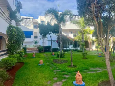 a garden in front of a building with palm trees at Évasion océanique skhirat in Skhirat