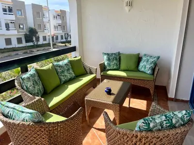 a patio with chairs and couches on a balcony at Évasion océanique skhirat in Skhirat
