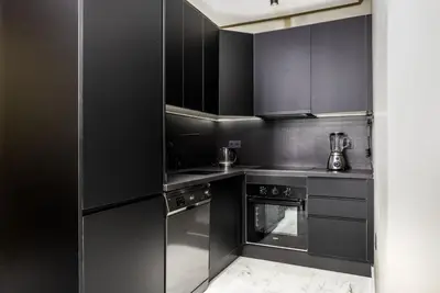 a black kitchen with stainless steel appliances and black cabinets at Luxury 1-Bedroom Apartment in Casablanca