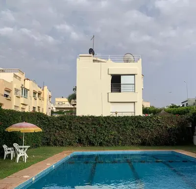 a house with a swimming pool and a table and an umbrella at Maison fantastique à louer à Harhoura près de la plage Votre maison côtière de rêve in Temara