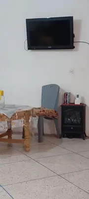 a table and a chair with a television on a wall at CasAmer in Temara