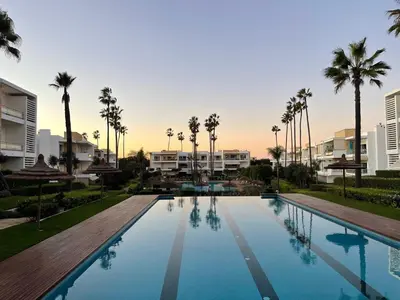 a large swimming pool with palm trees and buildings at Beachside Charming Apartment in Tamaris
