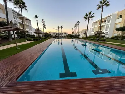 a swimming pool at a resort with palm trees at Beachside Charming Apartment in Tamaris