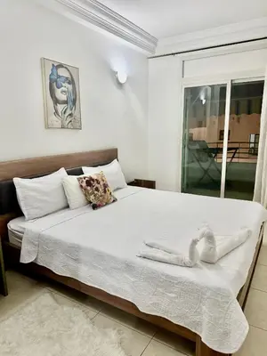 a bedroom with a bed with white sheets and a window at Appartement Agdal, proche des stades in Rabat