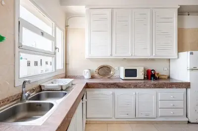 a kitchen with white cabinets and a sink and a microwave at Appartement Agdal, proche des stades in Rabat