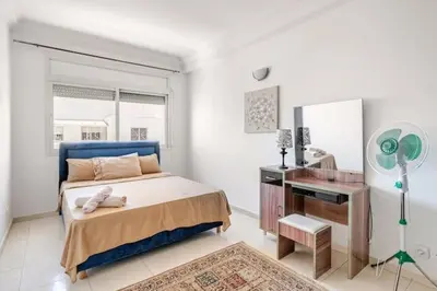 a bedroom with a bed and a desk with a fan at Appartement Agdal, proche des stades in Rabat