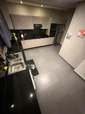 a kitchen with white cabinets and a white tile floor at Corniche in Casablanca