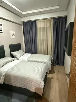 a bedroom with two beds and a tv and curtains at Corniche in Casablanca