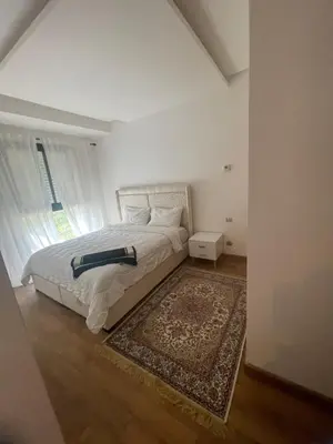 a white bedroom with a bed and a rug at Studio moderne et élégant Idéal pour un séjour confortable in Rabat