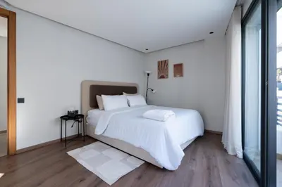 a white bedroom with a large bed and a window at Casablanca Maarif 1BR With Private Patio And Parking in Casablanca