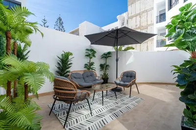 a patio with a table and chairs and an umbrella at Casablanca Maarif 1BR With Private Patio And Parking in Casablanca