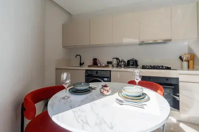 a kitchen with a white table and red chairs at Casablanca Maarif 1BR With Private Patio And Parking in Casablanca