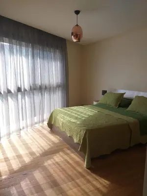 a bedroom with a green bed and a large window at Stunning one bedroom flat at Casablanca Marina 10th floor Sea View in Casablanca