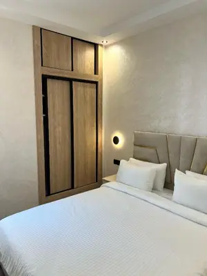 a bedroom with a white bed with a wooden door at Functional and Stylish Apartment in Agdal for Rabat Stay in Rabat