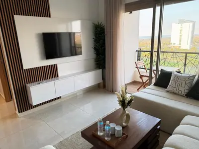 a living room with a couch and a tv on a wall at Évasion zen près de Casablanca - Vue imprenable sur le parc et la plage de l'Éco City Zenata in Aïn Harrouda