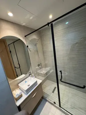 a bathroom with a sink and a glass shower at Évasion zen près de Casablanca - Vue imprenable sur le parc et la plage de l'Éco City Zenata in Aïn Harrouda