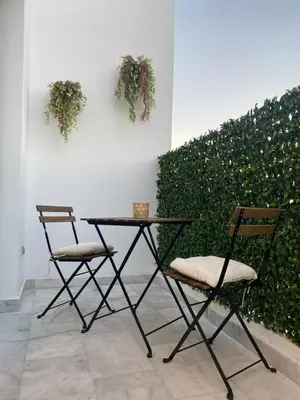 two chairs and a table with plants on a wall at Quartier l oasis prêt de la gare in Casablanca