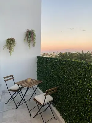 a table and chairs next to a green hedge at Quartier l oasis prêt de la gare in Casablanca