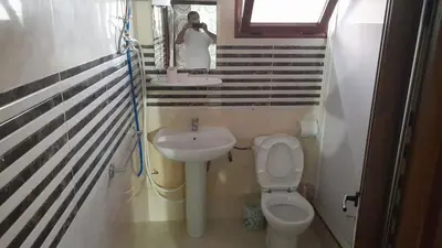 a person taking a picture of a bathroom with a toilet and sink at Old school in Rabat