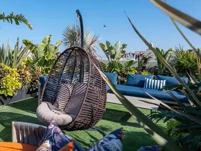 a wicker swing sitting on a patio with pillows at Cozy & Modern Apartment with Rooftop Gym Great Casablanca Location in Casablanca