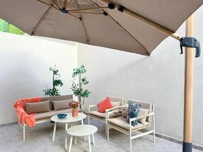 a patio with two chairs and a table and an umbrella at Cosy Patio sunny 2BR - new building - near oasis train station in Casablanca