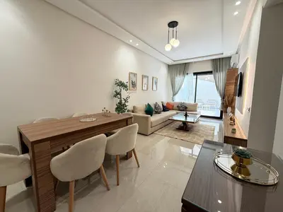 a living room with a table and chairs and a couch at Cosy Patio sunny 2BR - new building - near oasis train station in Casablanca