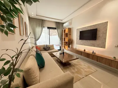a living room with a couch and a tv at Cosy Patio sunny 2BR - new building - near oasis train station in Casablanca