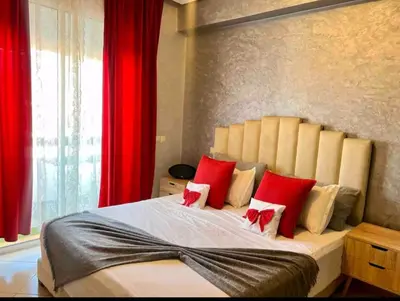 a bedroom with a large bed with red pillows at Appartement moderne bord de mer in Sidi Rahal