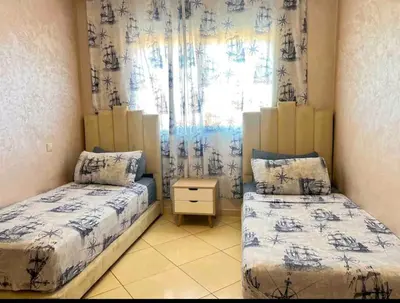 a bedroom with two beds and a window with curtains at Appartement moderne bord de mer in Sidi Rahal