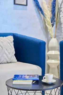 a blue couch with a table with a coffee cup and books at Luxury 3 Bedroom Getaway in Bouskouras Finest in Bouskoura