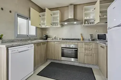 a kitchen with white appliances and wooden cabinets at Family-Friendly 3BR with Garden and Outdoor Space in Bouskoura