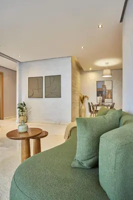 a living room with a green couch and a table at Family-Friendly 3BR with Garden and Outdoor Space in Bouskoura