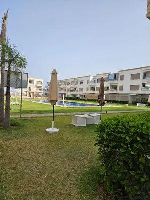 two umbrellas sitting in the grass near a building at vacance à Mansouria P Banus in Mansouria