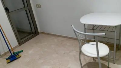 a chair sitting next to a table and a window at Bel Appartement Confort et Commodités au Cœur de Casablanca Belvédère in Casablanca