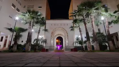 a building with a fountain in a courtyard with palm trees at Appartement Magnifique au coeur de la Corniche de Rabat in Rabat