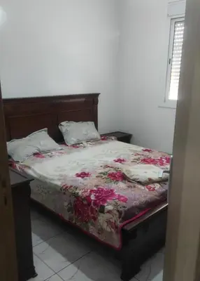 a bedroom with a bed with a floral comforter at Alia Apartment 25 in Casablanca
