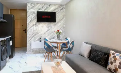 a living room with a couch and a table with chairs at Elégant et moderne appartement à 10 min du centre de Casablanca in Casablanca