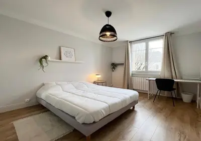 a white bedroom with a bed and a desk and a window at Appartement cosyy in Casablanca