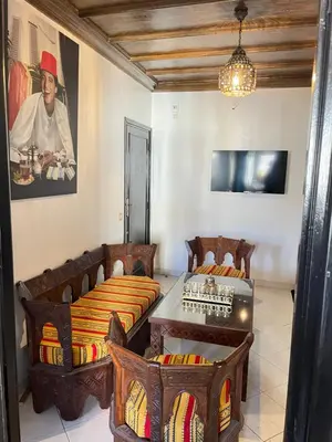 a living room with two beds and a table at Suite des lumières Al Malaki Offre Spéciale front Mer, Zéro Surprise- l'Accueil Aéroport & Service Cuisine si besoin de Tranquillité Totale in Rabat
