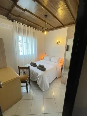 a bedroom with a large white bed and a chair at Suite des lumières Al Malaki Offre Spéciale front Mer, Zéro Surprise- l'Accueil Aéroport & Service Cuisine si besoin de Tranquillité Totale in Rabat