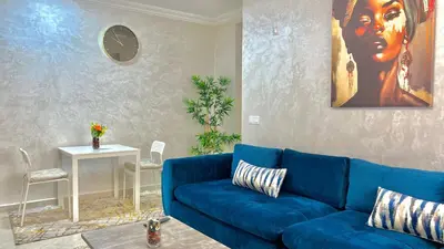a living room with a blue couch and a clock at T6 Luxury in Témara Discover a Comfortable Apartment in Temara