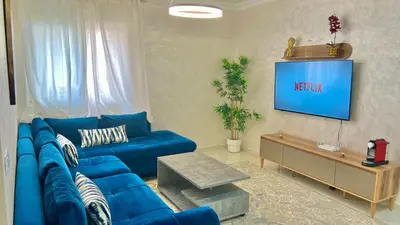 a living room with a blue couch and a television at T6 Luxury in Témara Discover a Comfortable Apartment in Temara