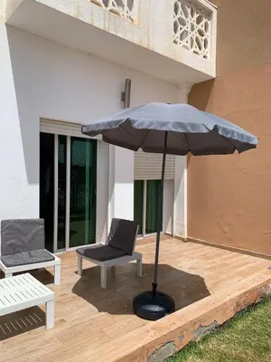 an umbrella and a chair on a wooden deck at Al Kawtar in Mansouria